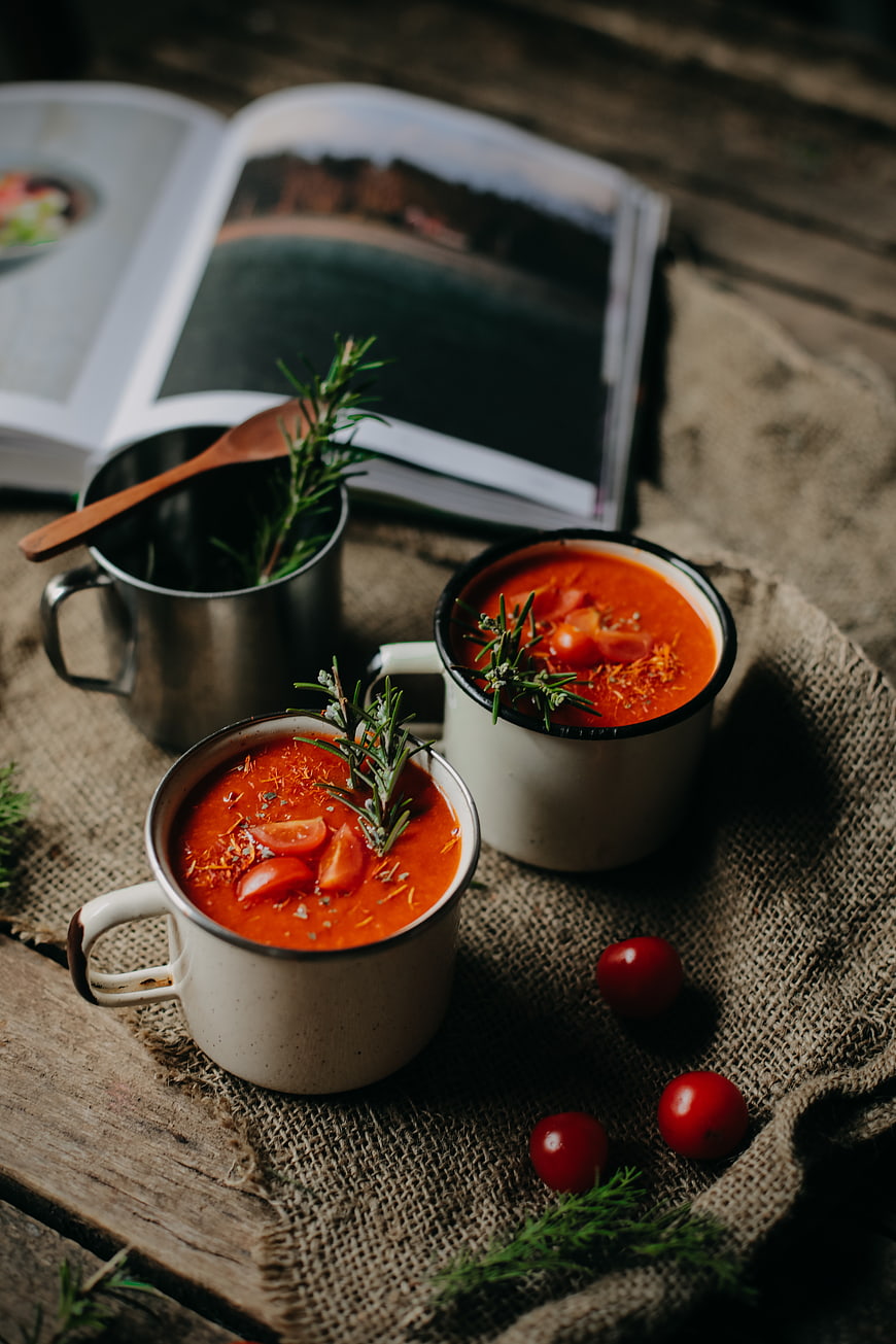 Rustic tomato soup in enamel mugs with rosemary