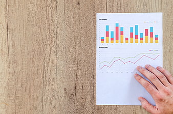 Business Financial Charts On Paper With Hand On Wooden Desk