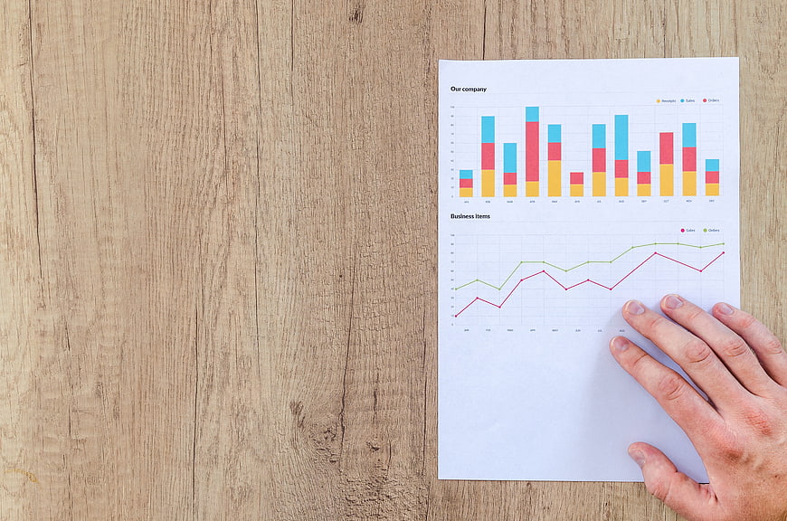 Business Financial Charts On Paper With Hand On Wooden Desk