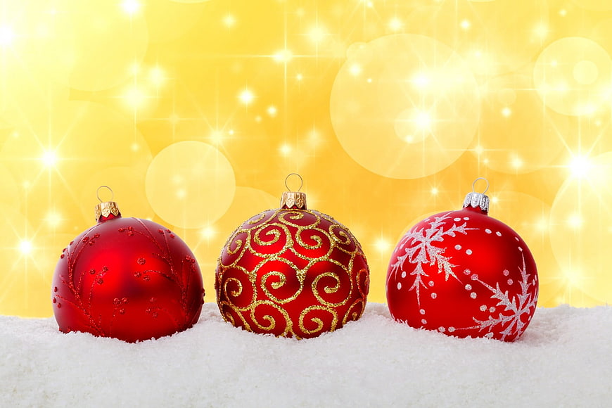 Three Red Christmas Ornaments on Snow with Golden Bokeh Background