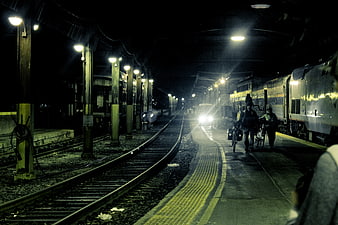 Night scene at a railway station with trains and cyclists