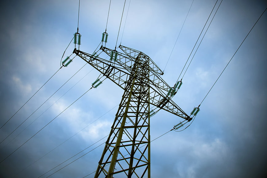 Low angle view of high voltage electricity pylon against cloudy sky