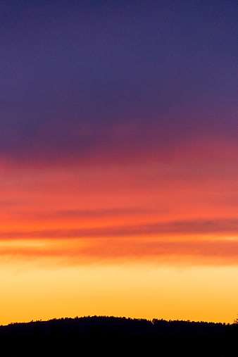 Vibrant sunset sky with purple, orange, and yellow gradient over silhouette