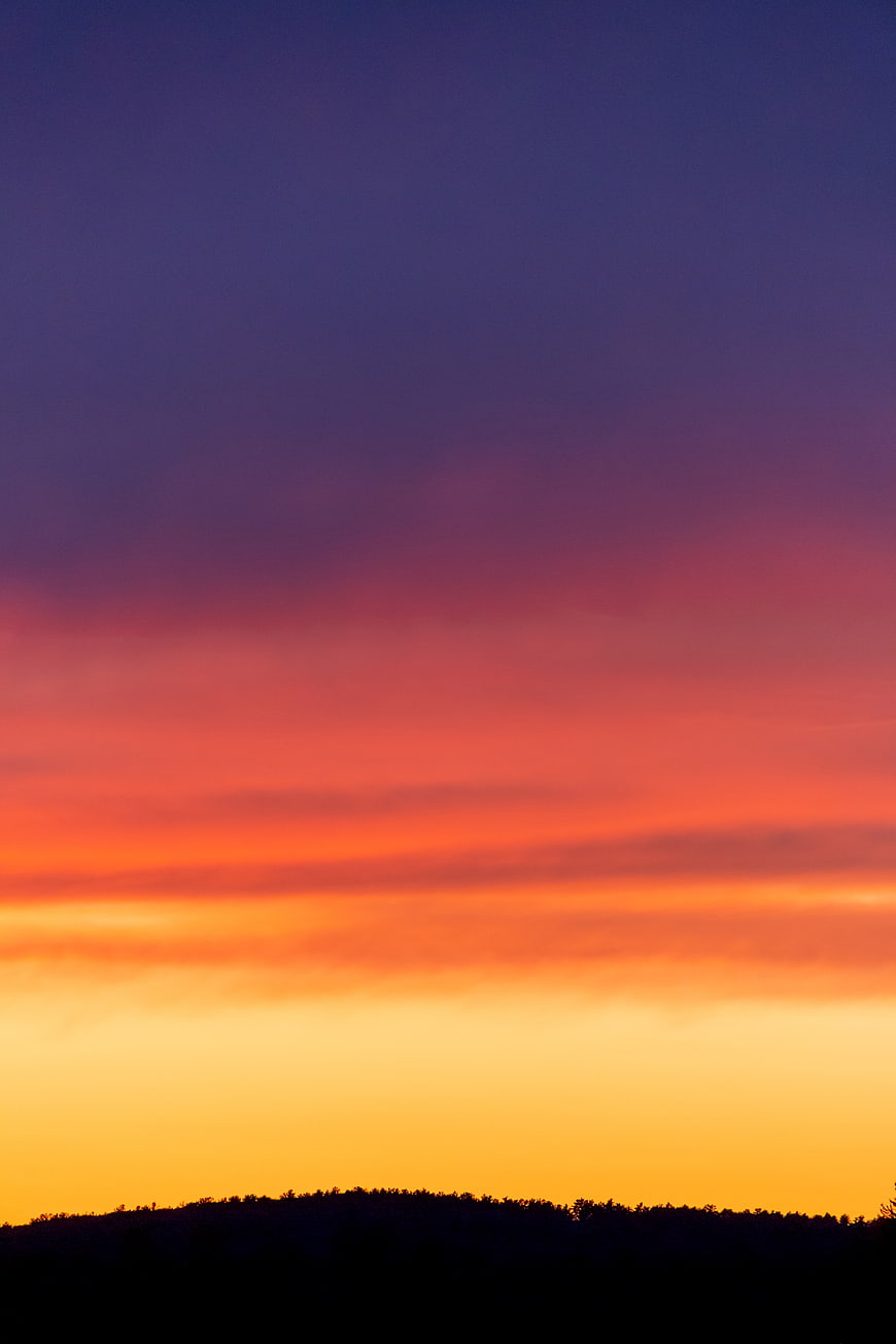 Vibrant sunset sky with purple, orange, and yellow gradient over silhouette