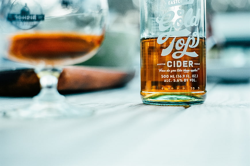 Gold Top Cider Bottle and Glass on Wooden Table