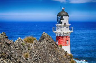 Cape Palliser Lighthouse on Rocky Coastline with Blue Ocean