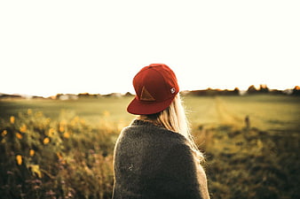 Woman in Red Cap Looking at Field at Sunset