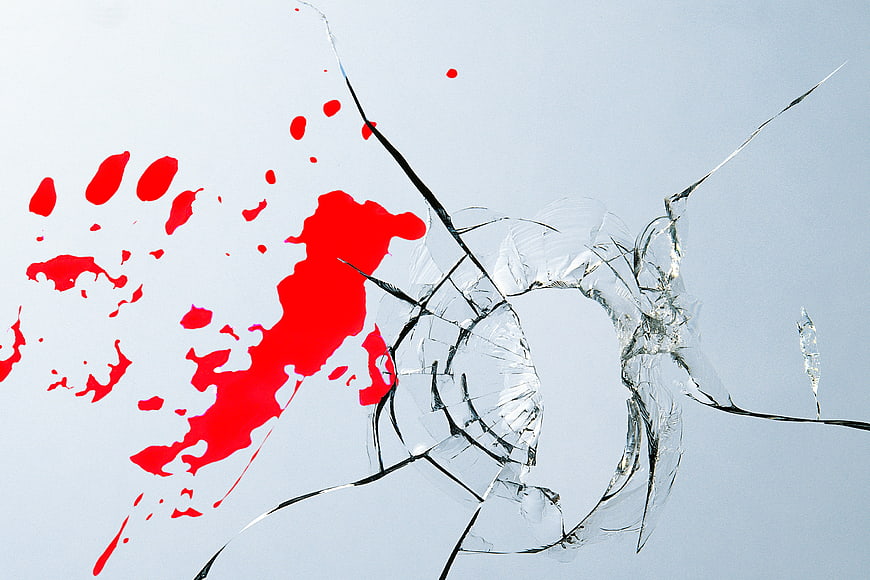 Shattered glass with red paint splatter and handprint on white background