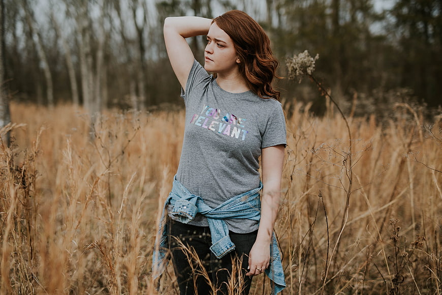 Young woman with red hair in field wearing relevant t-shirt