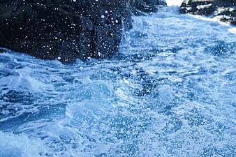 Dynamic Blue Ocean Waves Crashing Against Dark Rocks