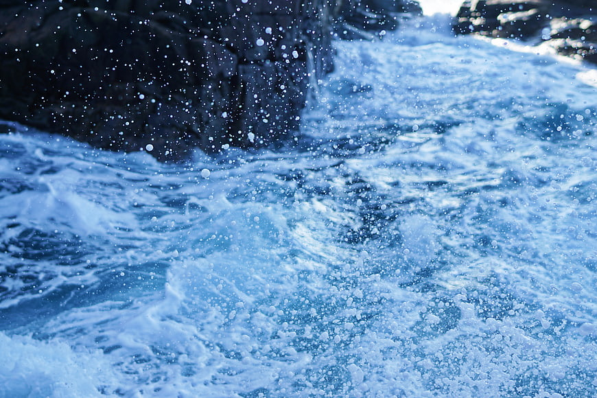 Dynamic Blue Ocean Waves Crashing Against Dark Rocks