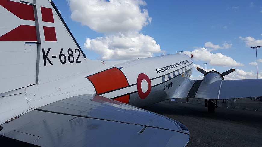 Vintage propeller airplane tail with red markings on airfield