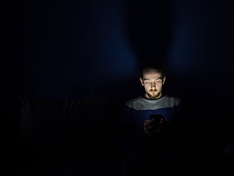 Man using smartphone in dark room at night