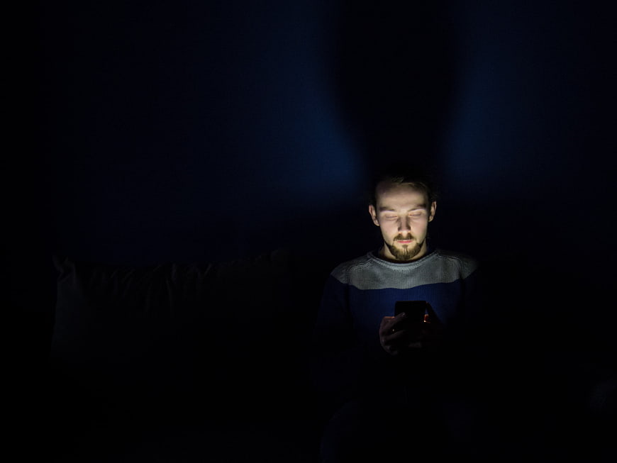 Man using smartphone in dark room at night