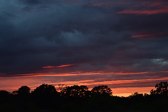 Dramatic Sunset Sky with Dark Clouds and Silhouetted Trees