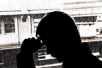 Silhouette of man looking out rainy window