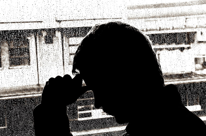 Silhouette of man looking out rainy window