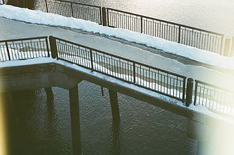 Snowy urban bridge walkway over water in winter