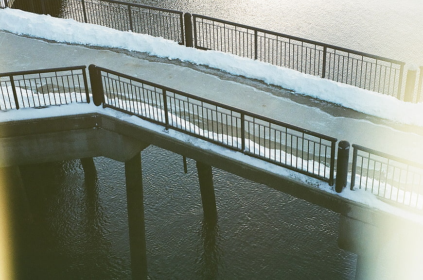 Snowy urban bridge walkway over water in winter