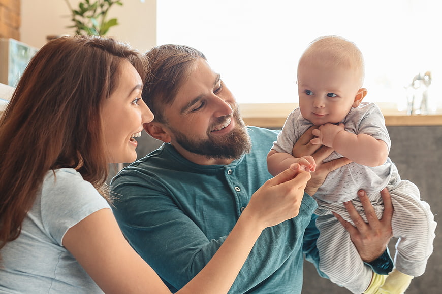 Happy Young Family Playing with Baby at Home