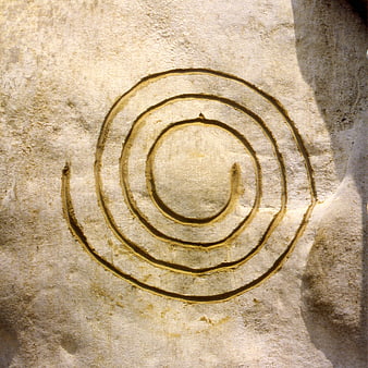 Ancient spiral symbol carved into textured sandstone rock surface