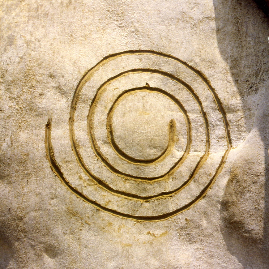 Ancient spiral symbol carved into textured sandstone rock surface