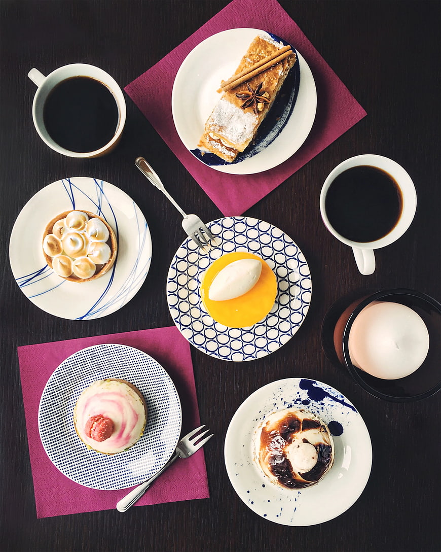 Overhead view of assorted desserts and coffee on dark table