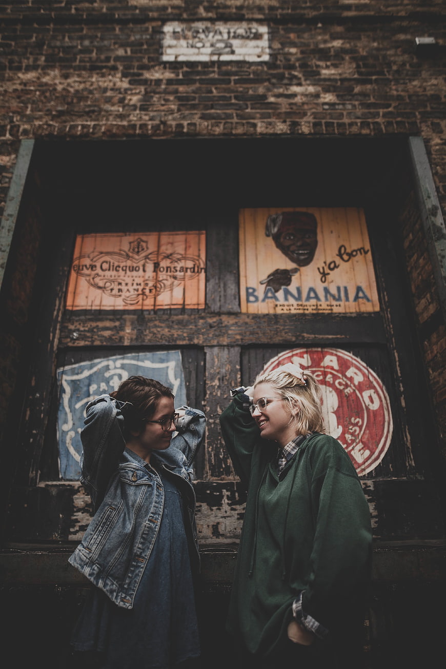 Two women laughing in front of vintage painted wooden doors