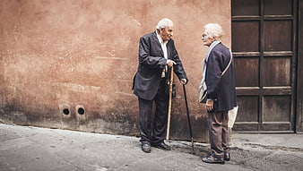 Two elderly people talking on a street corner