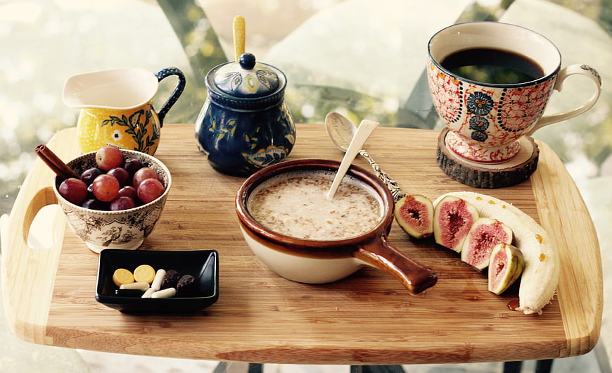 Healthy breakfast with oatmeal, fresh fruit, and coffee on wooden tray