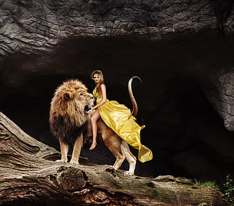 Woman in yellow dress riding a roaring lion in a dark cave