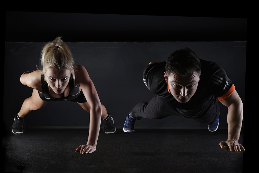 Athletic Man and Woman Doing Push-Ups in Dark Gym