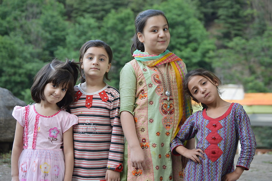 Four young girls posing outdoors in colorful traditional clothing