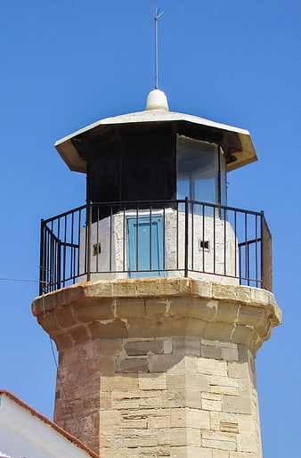 Old stone lighthouse tower against clear blue sky