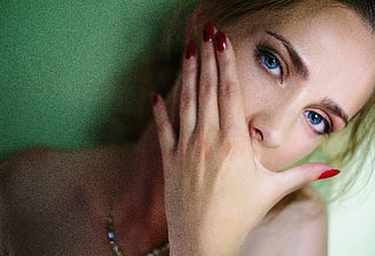 Close-up portrait of a woman with blue eyes and red nails