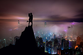 Silhouette of Lovers on Mountain Peak Over City Skyline