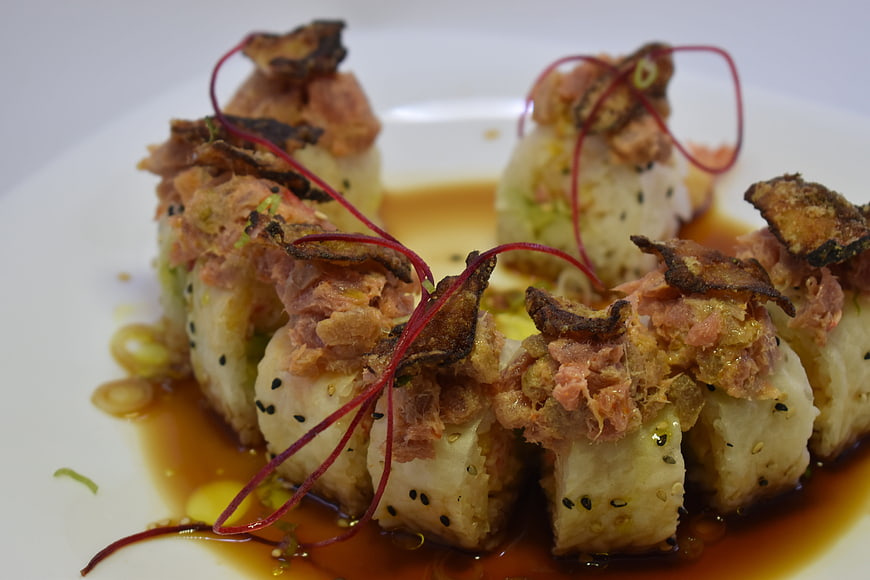 Gourmet sushi roll with crispy topping and soy sauce