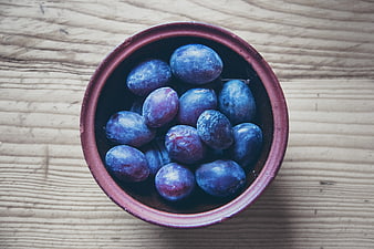 Top View of Blue Plums in a Rustic Ceramic Bowl