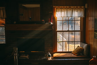 Cozy rustic interior with sunlit window seat and brick fireplace