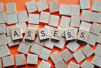 Wooden Scrabble Tiles Spelling Assess on Orange Background