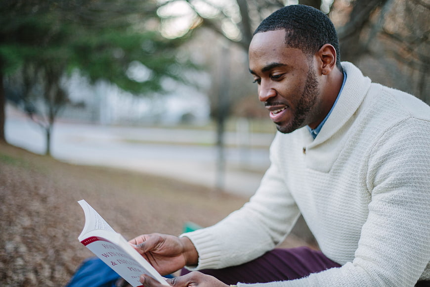 Happy African American Man Reading Book Outdoors