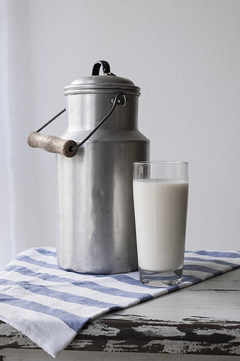 Vintage metal milk can and glass of milk on striped cloth