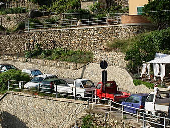Parked cars on a winding street with stone retaining walls