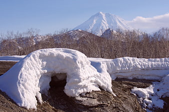 Snow cave in foreground with Koryaksky volcano background