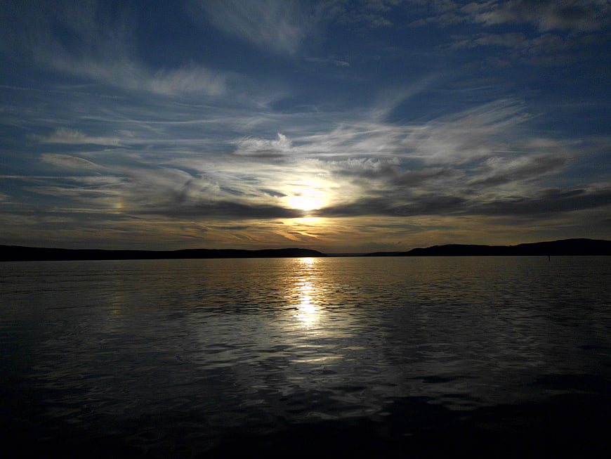 Serene Sunset Over Lake with Cloudy Sky and Water Reflection
