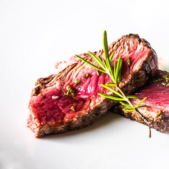 Sliced medium-rare steak with rosemary garnish on white background
