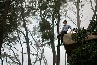 Man sitting on rock in foggy forest