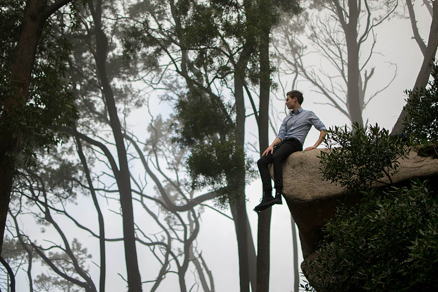 Man sitting on rock in foggy forest