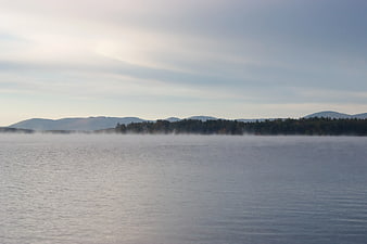 Misty Lake Landscape with Distant Mountains and Forest