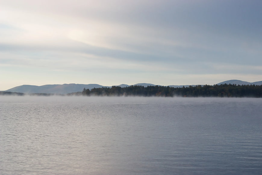 Misty Lake Landscape with Distant Mountains and Forest